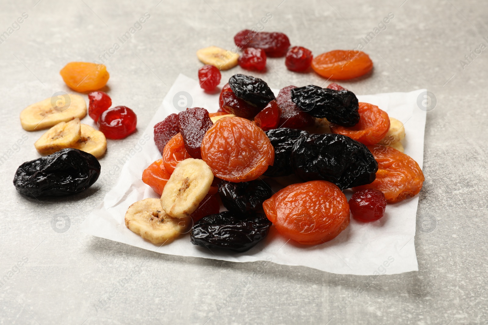 Photo of Mix of delicious dried fruits on grey table, closeup