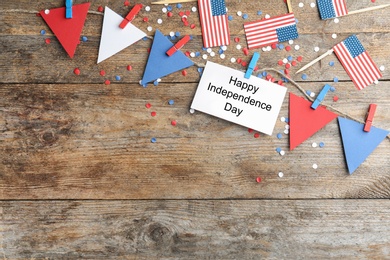 Photo of Flat lay composition with greeting card on wooden table, space for text. USA Independence Day