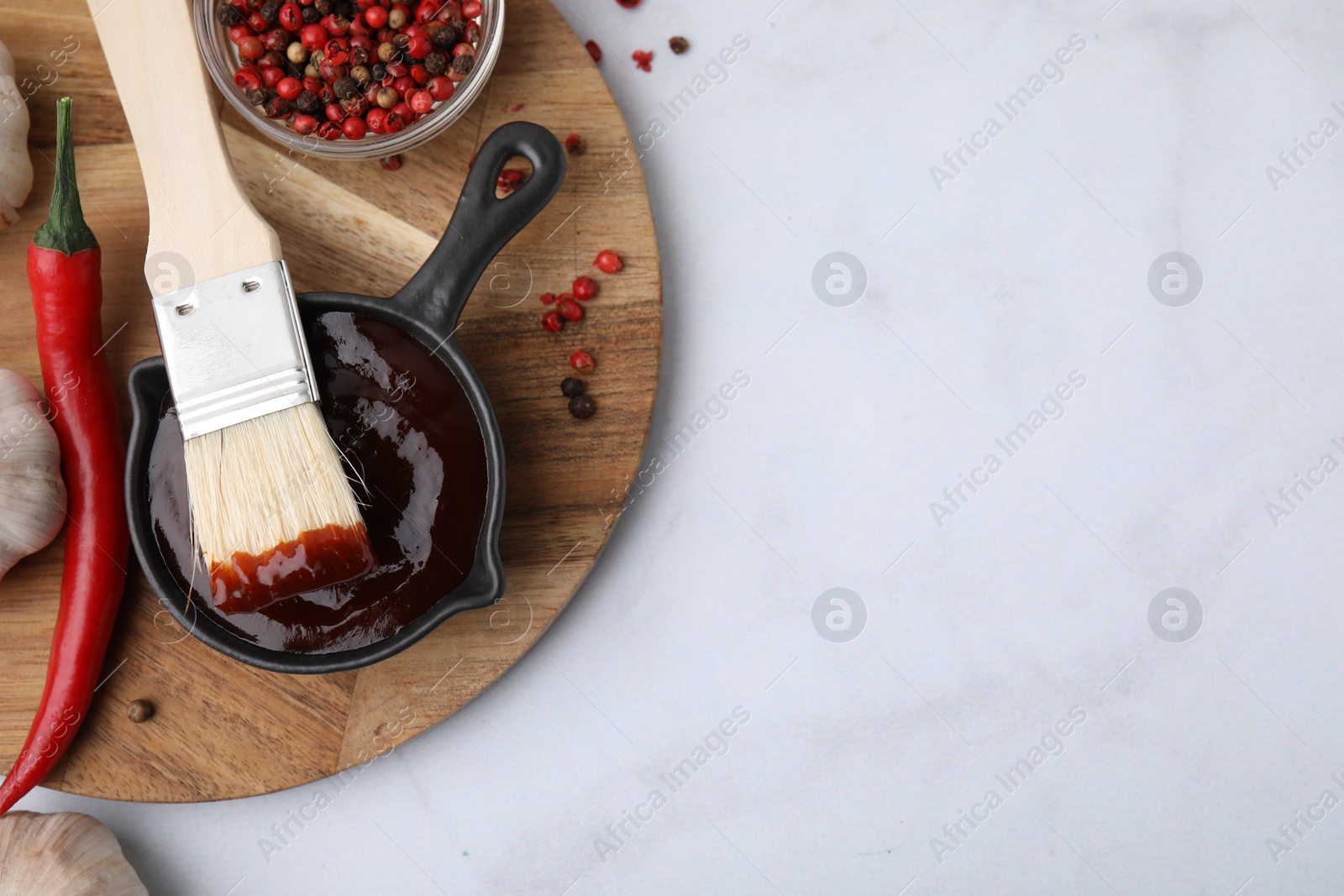 Photo of Marinade in gravy boat, ingredients and basting brush on white marble table, flat lay. Space for text