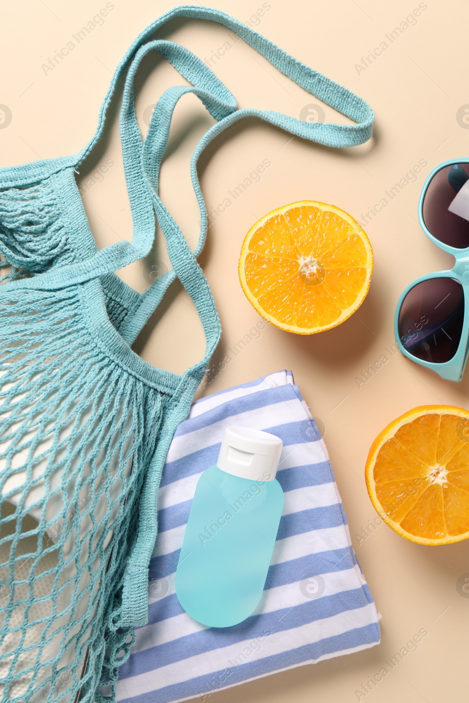 Photo of String bag, different beach accessories and orange on beige background, flat lay