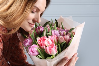 Photo of Young woman with bouquet of beautiful tulips indoors, closeup