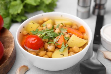 Tasty chickpea soup in bowl served on light grey table, closeup