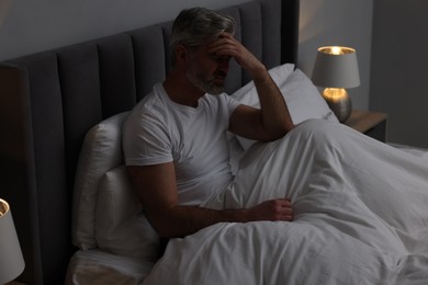 Photo of Mature man suffering from headache in bed at night