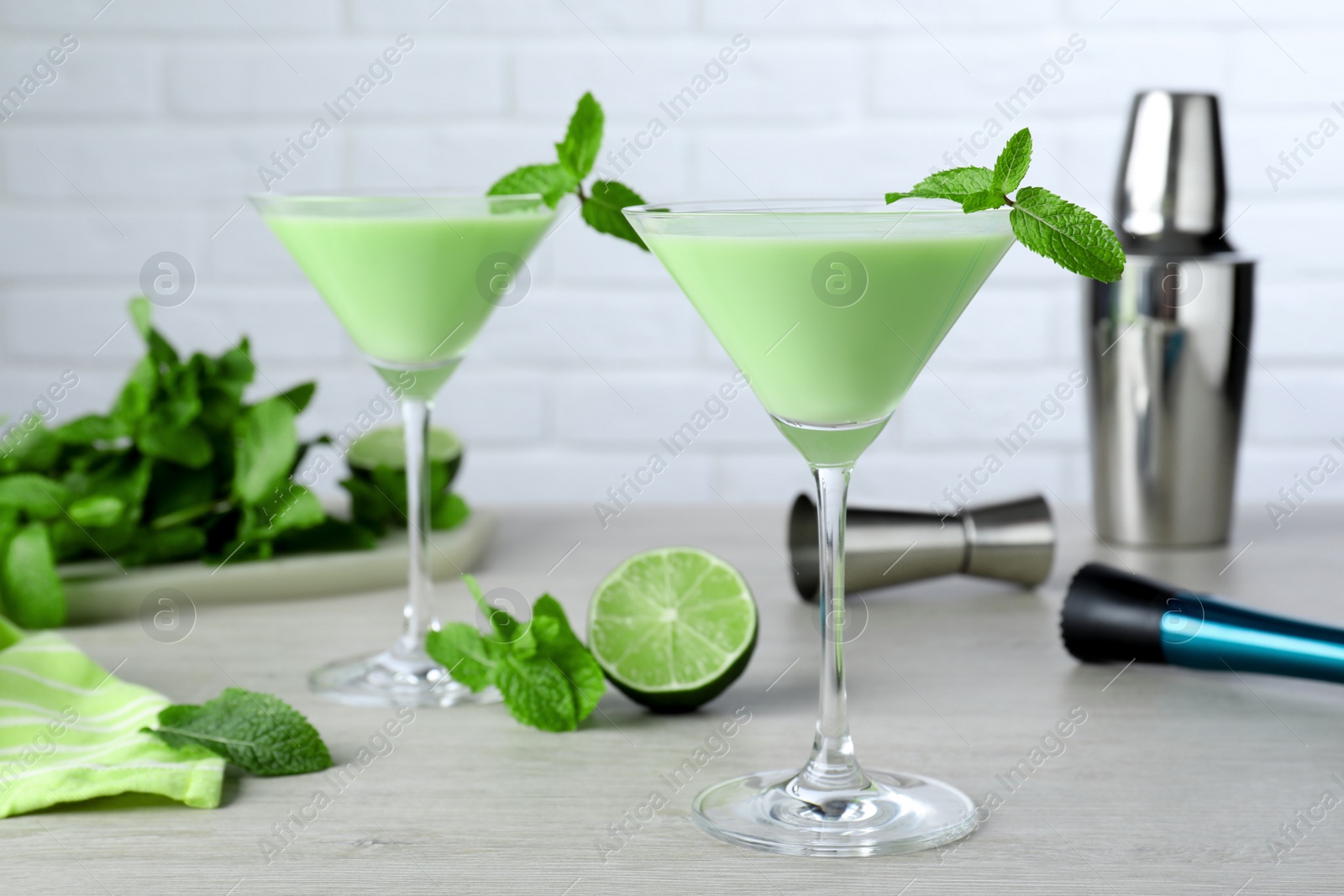 Photo of Delicious mint liqueur with green leaves on white wooden table