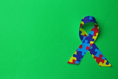 Image of World Autism Awareness Day. Colorful puzzle ribbon on green background, top view with space for text