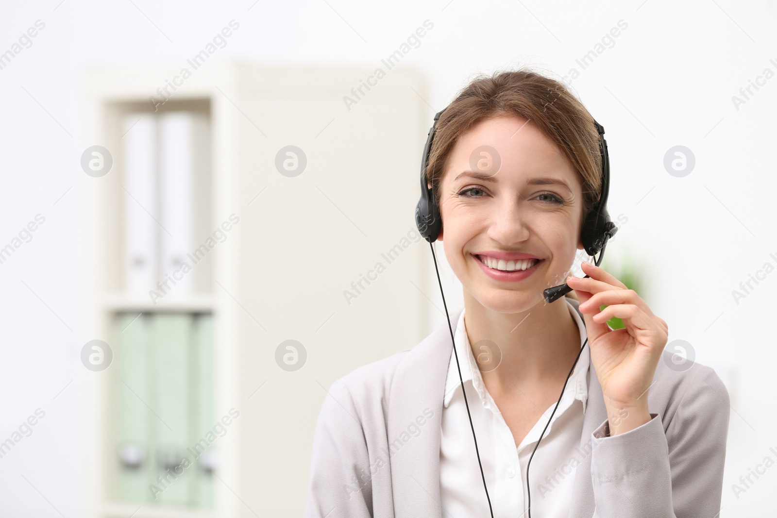 Photo of Young female receptionist with headset in office