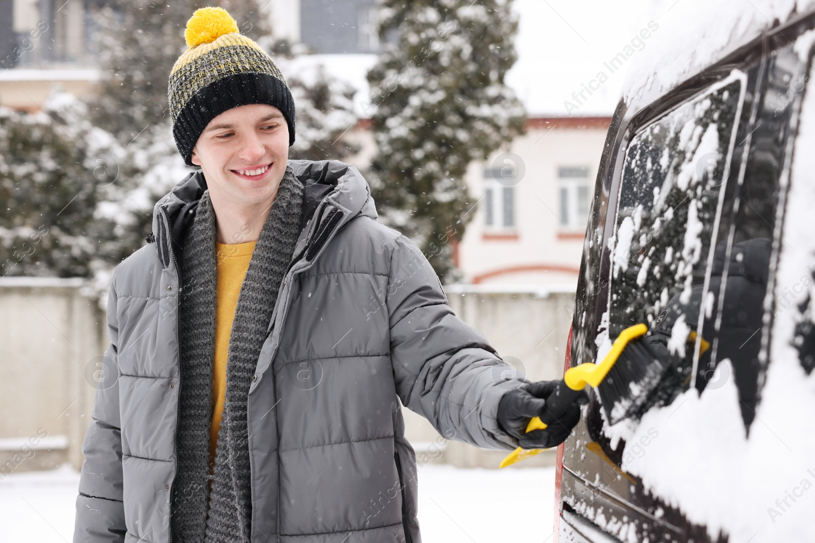 Photo of Man cleaning snow from car window outdoors