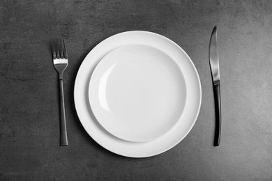 Photo of Empty dishware and cutlery on gray background, top view. Table setting
