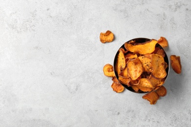 Photo of Bowl and sweet potato chips on light table, top view. Space for text