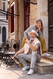 Photo of Smiling affectionate senior couple on doorstep outdoors
