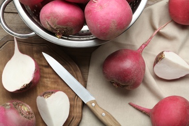 Photo of Red turnips and knife on wooden table, flat lay