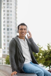 Handsome young African-American man with headphones listening to music on city street