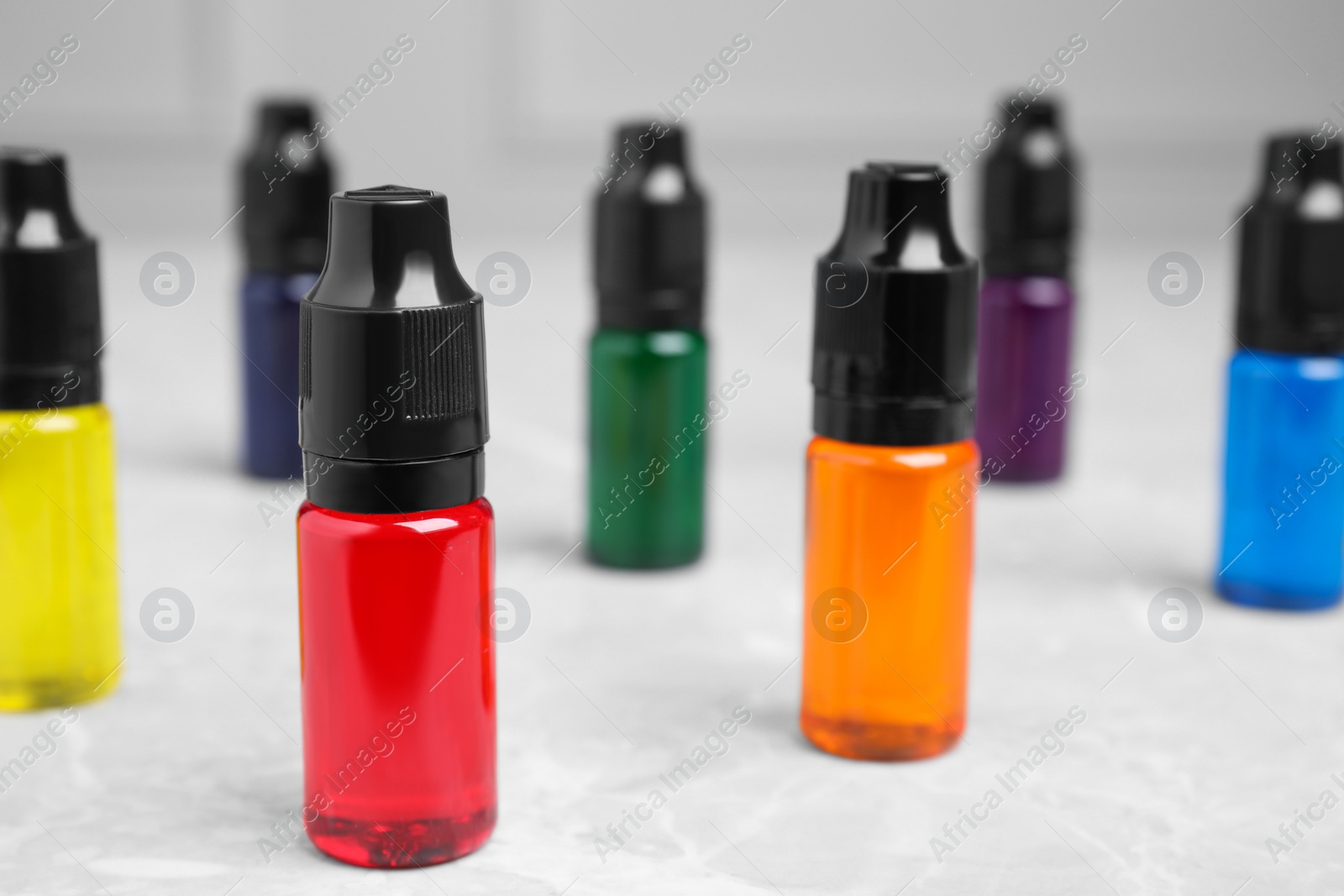 Photo of Bottles with different food coloring on white table, closeup. Space for text