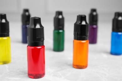 Bottles with different food coloring on white table, closeup. Space for text