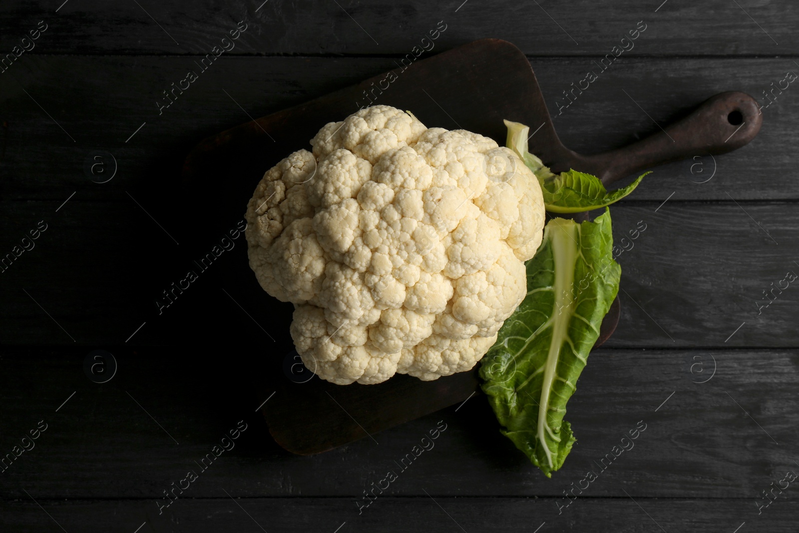 Photo of Fresh raw cauliflower on black wooden table, top view