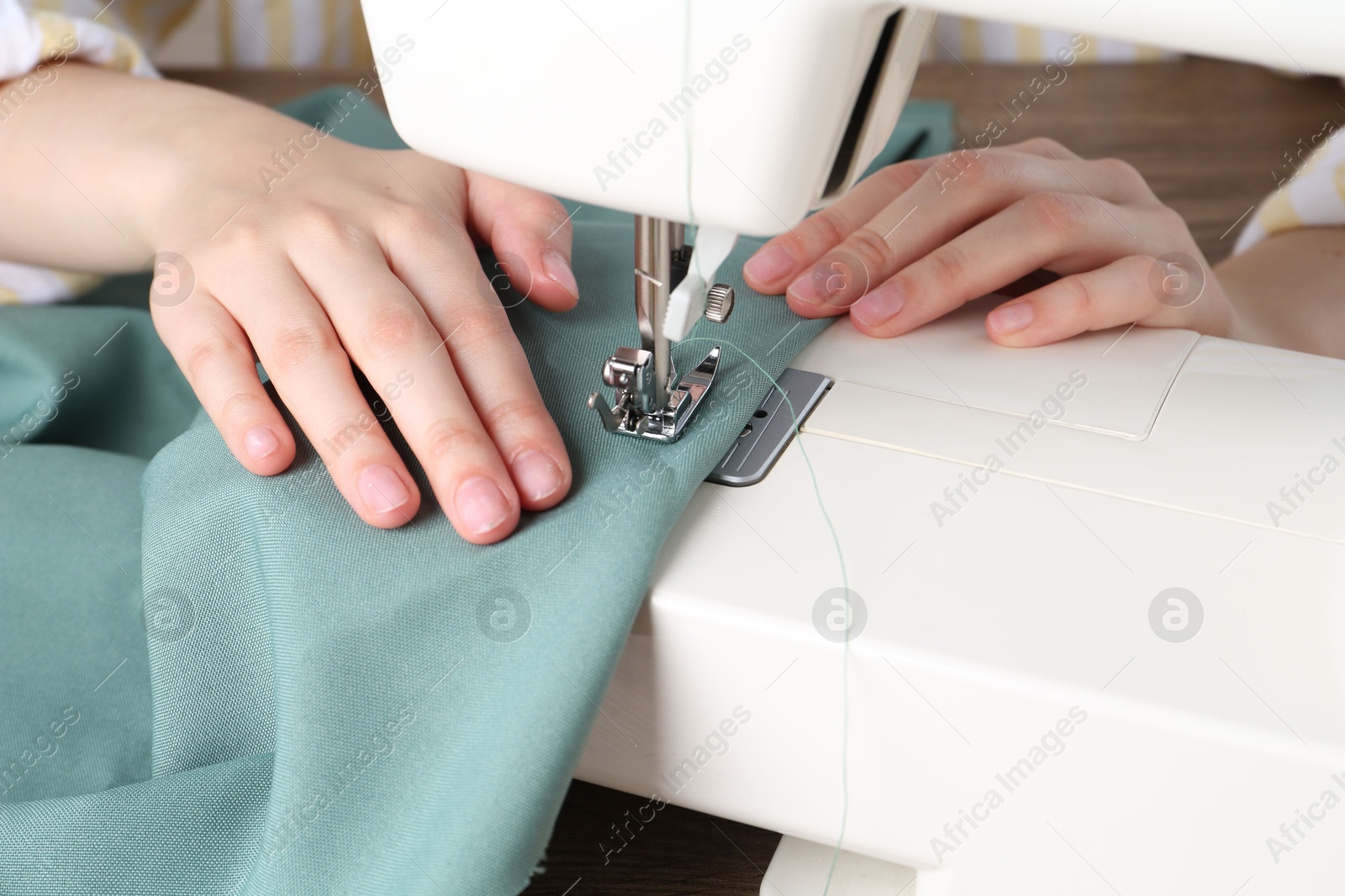 Photo of Seamstress working with sewing machine indoors, closeup