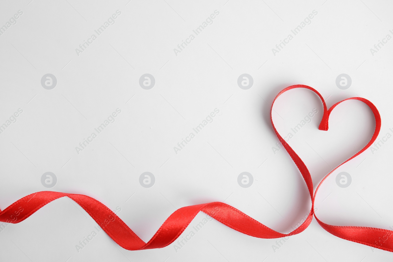 Photo of Heart made of red ribbon on white background, top view. Valentine's day celebration