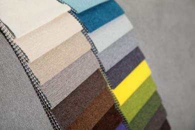 Photo of Catalog of colorful fabric samples on grey background, closeup