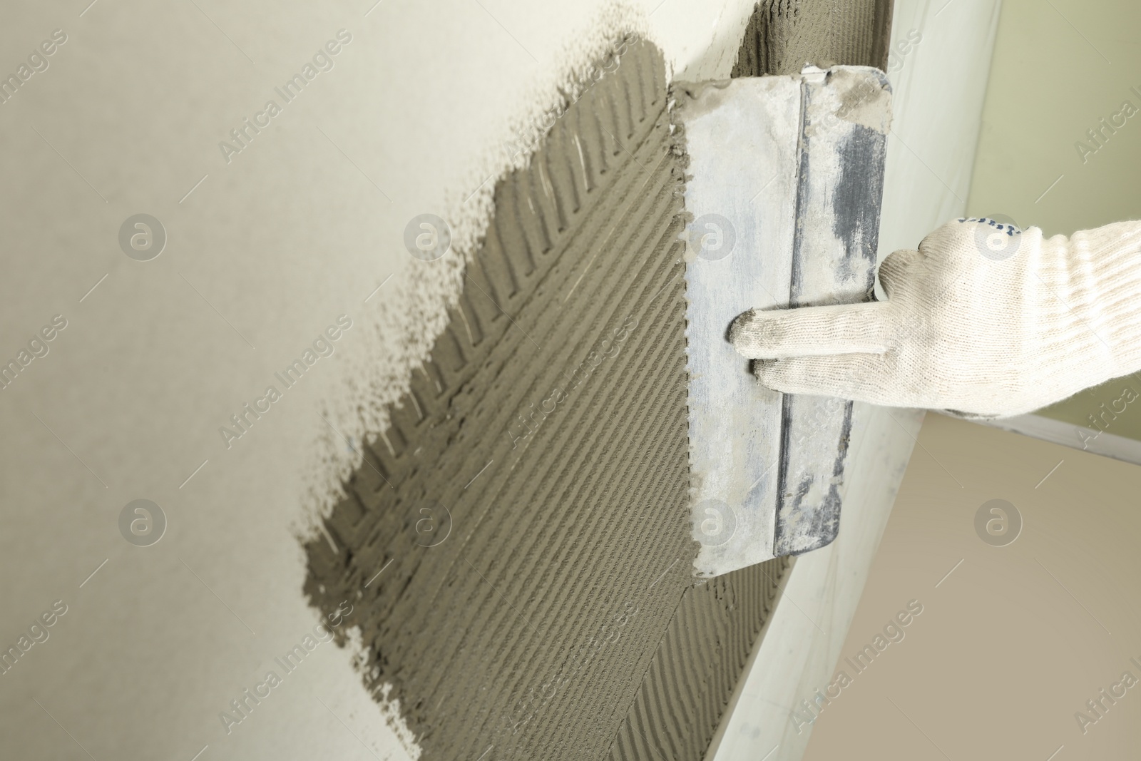 Photo of Closeup of worker spreading concrete on wall with spatula, space for text. Tile installation