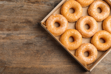 Photo of Delicious donuts on wooden table, top view. Space for text