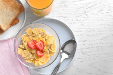 Flat lay composition with cornflakes and strawberries on white wooden table, space for text. Healthy breakfast