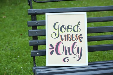 Photo of Poster with phrase Good Vibes Only on black wooden bench outdoors