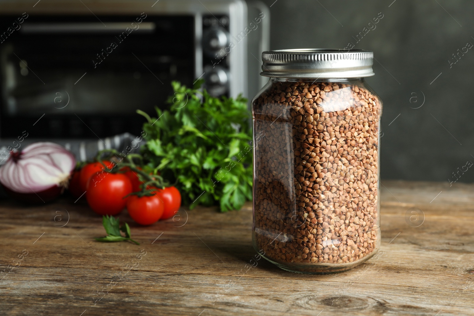 Photo of Buckwheat grains in jar on wooden table. Space for text