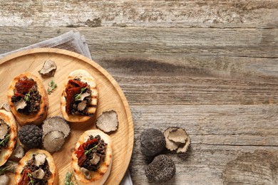 Delicious bruschettas with truffle sauce and sun dried tomatoes on wooden table, flat lay. Space for text