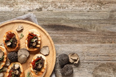 Photo of Delicious bruschettas with truffle sauce and sun dried tomatoes on wooden table, flat lay. Space for text