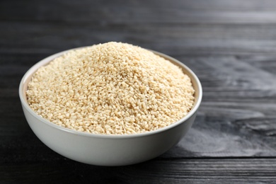 Photo of Sesame seeds in bowl on black wooden table