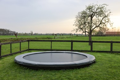 Spacious backyard with trampoline and wooden fence in evening