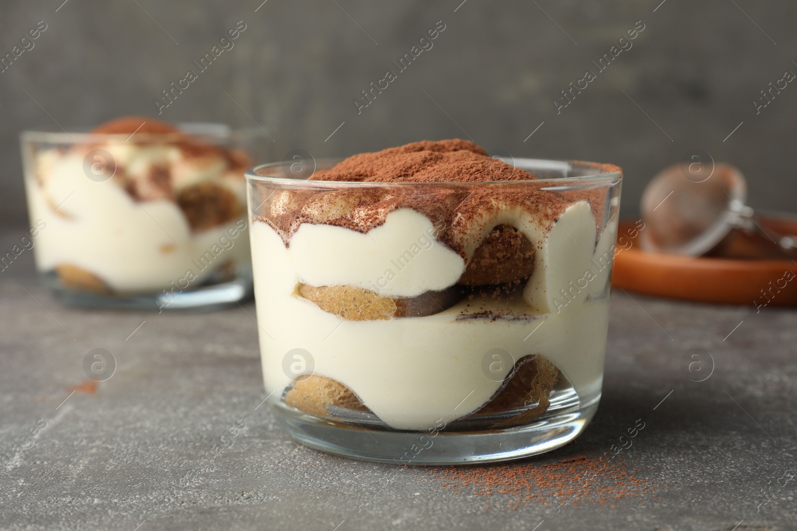 Photo of Delicious tiramisu in glass on grey table