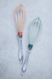 Two whisks on gray table, top view