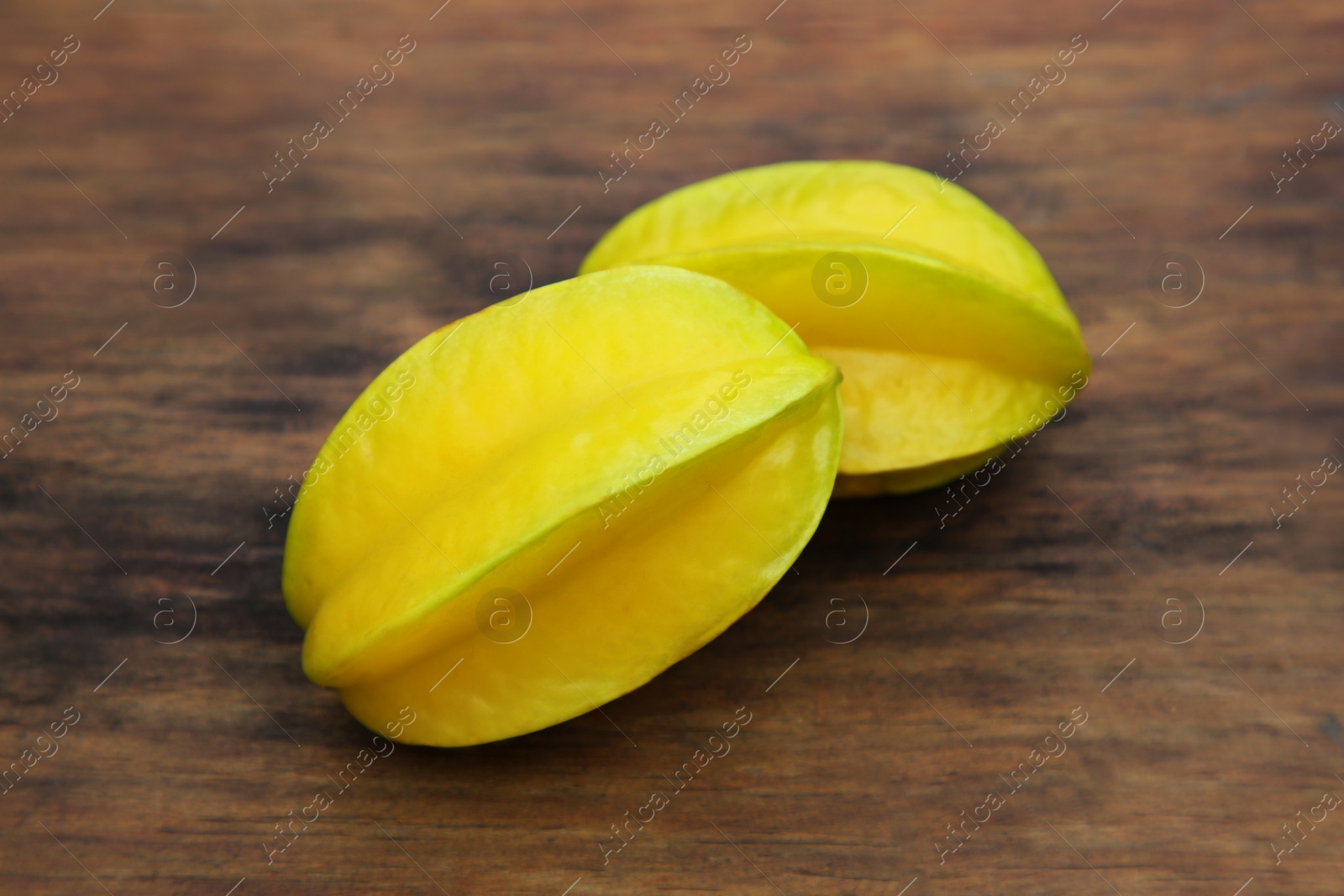 Photo of Delicious ripe carambolas on wooden table, closeup