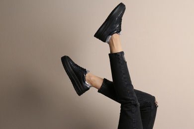 Woman wearing shoes on beige background, closeup