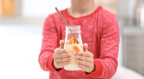 Photo of Little boy with yogurt in kitchen, closeup