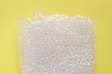 Photo of Transparent bubble wrap on yellow background, top view