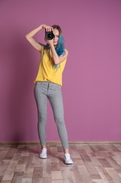 Young female photographer with camera near color wall