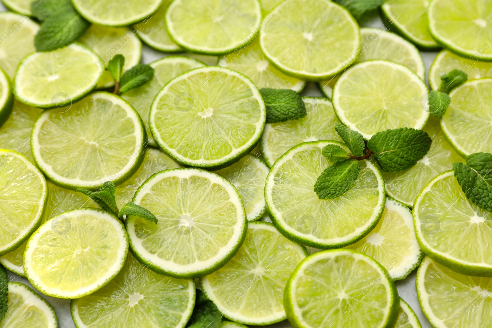 Photo of Slices of fresh juicy limes as background, closeup