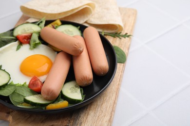 Photo of Delicious breakfast with boiled sausages and fried egg on white tiled table