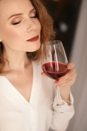 Woman with glass of delicious wine indoors