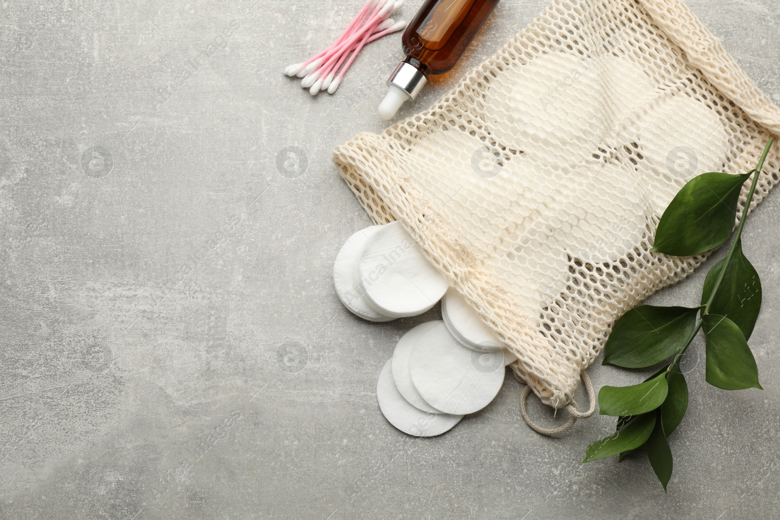 Photo of Cotton pads, swabs and makeup removal product on grey table, flat lay. Space for text