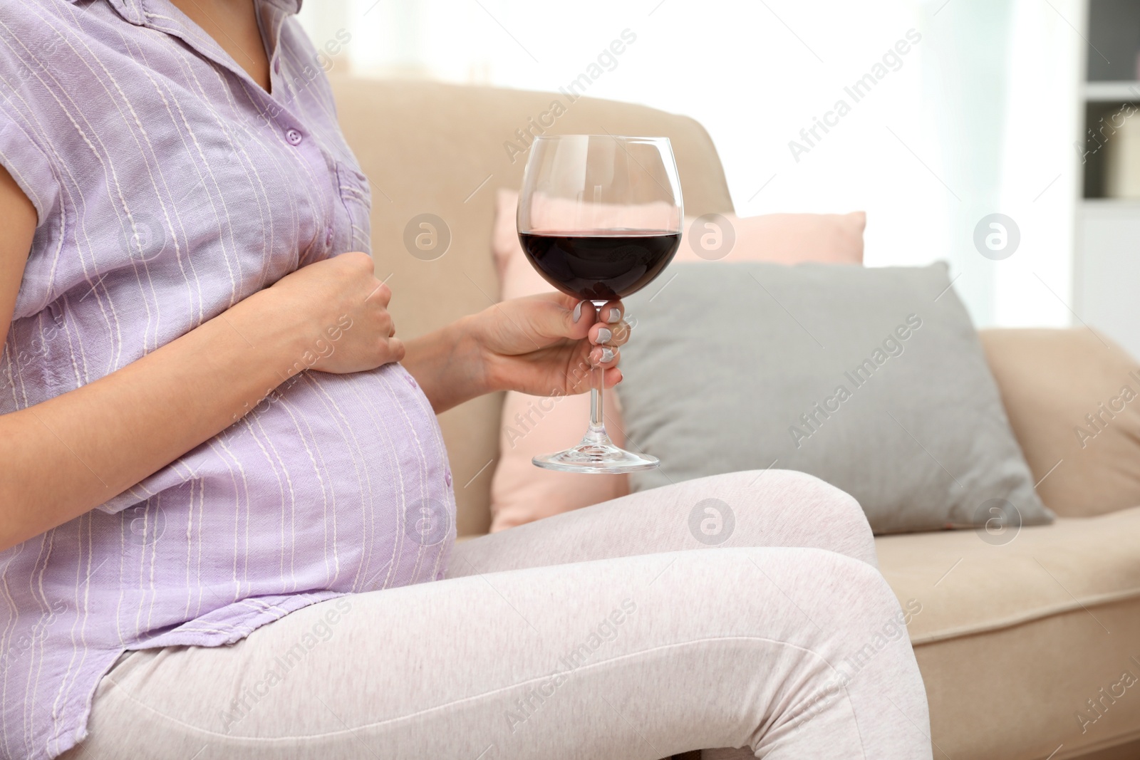 Photo of Future mother with glass of wine at home, closeup. Alcohol abuse during pregnancy