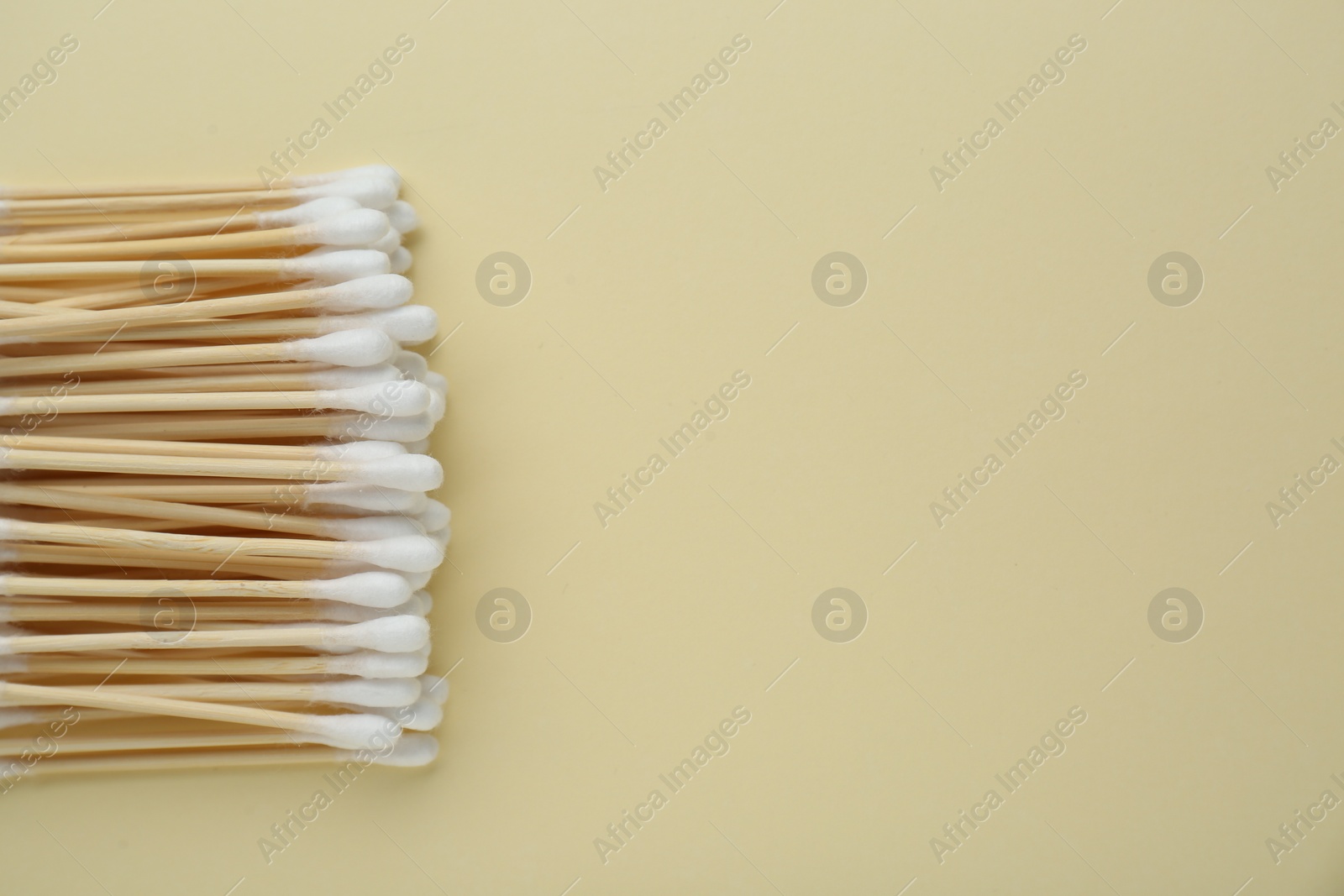 Photo of Many wooden cotton buds on beige background, flat lay. Space for text