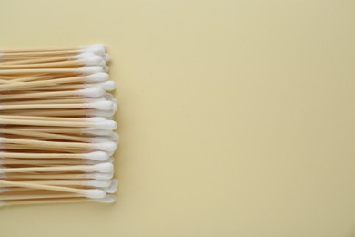 Many wooden cotton buds on beige background, flat lay. Space for text