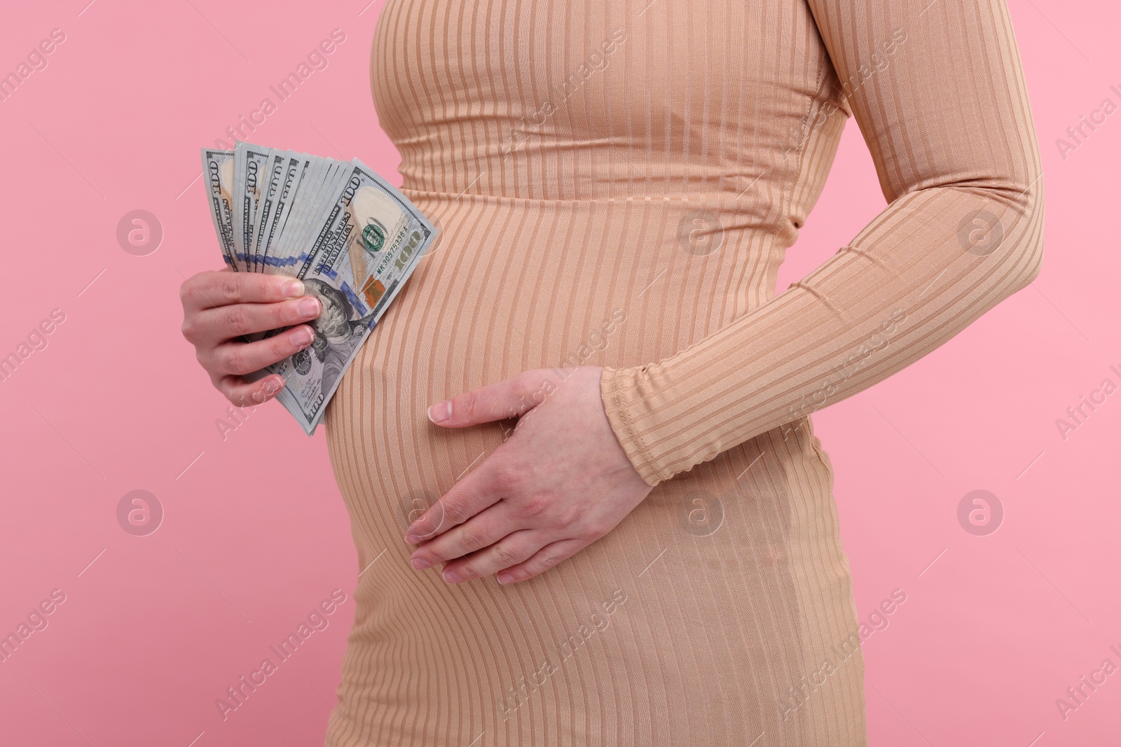 Photo of Surrogate mother. Pregnant woman with dollar banknotes on pink background, closeup