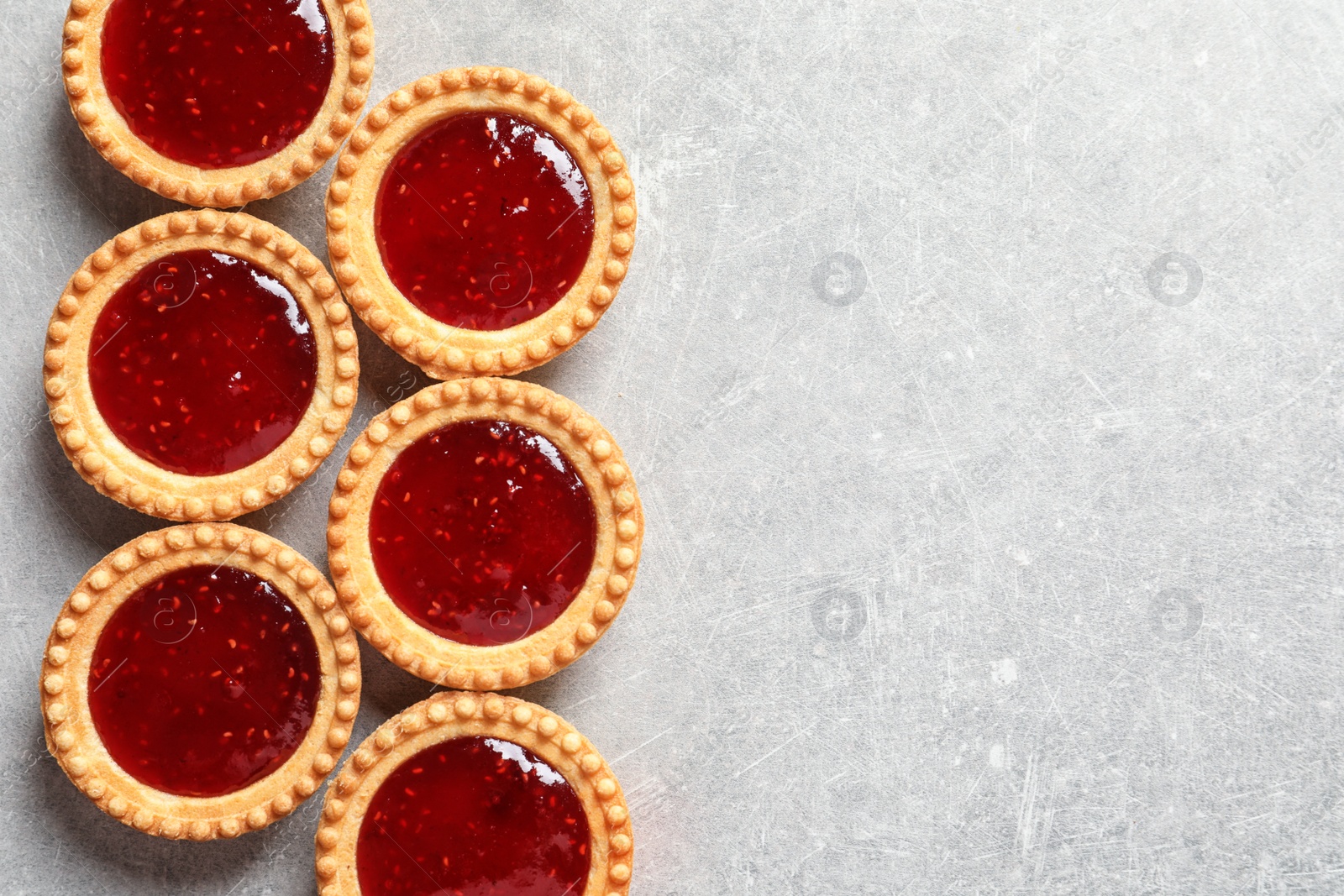 Photo of Tasty tartlets with jam on grey background