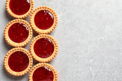 Photo of Tasty tartlets with jam on grey background