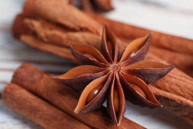 Photo of Aromatic anise star and cinnamon sticks on white wooden table, closeup