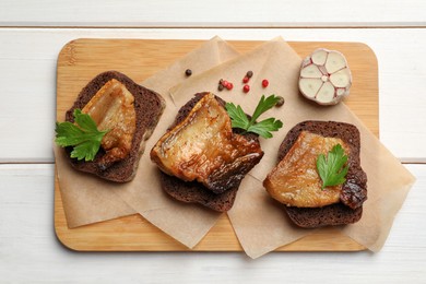 Photo of Rye bread with tasty fried cracklings on white wooden table, top view. Cooked pork lard